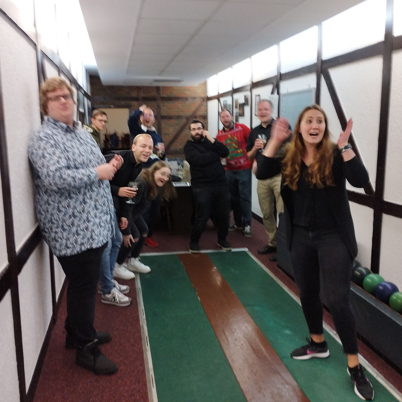 Gruppe von etwa 8 Personen, die vor einer Kegelbahn zusammenstehen und Spaß haben 