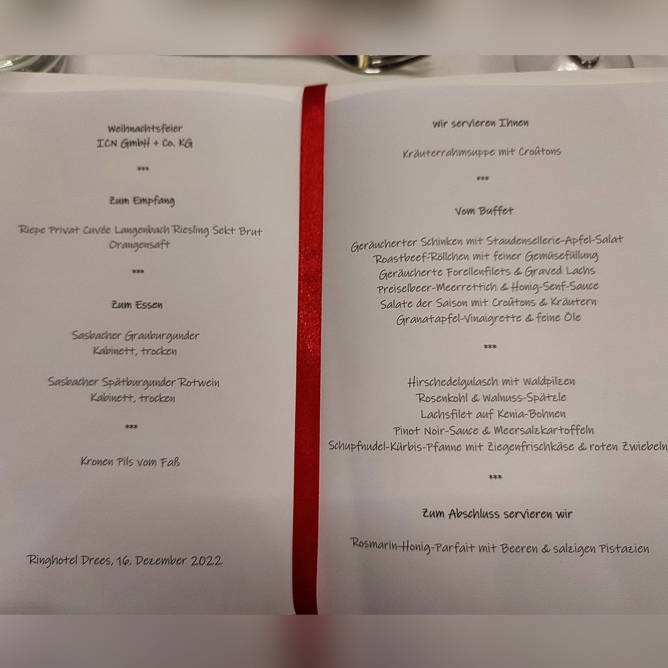 aufgeschlagenes Buch, das in der Mitte durch ein rotes Lesezeichenband geteilt wird 